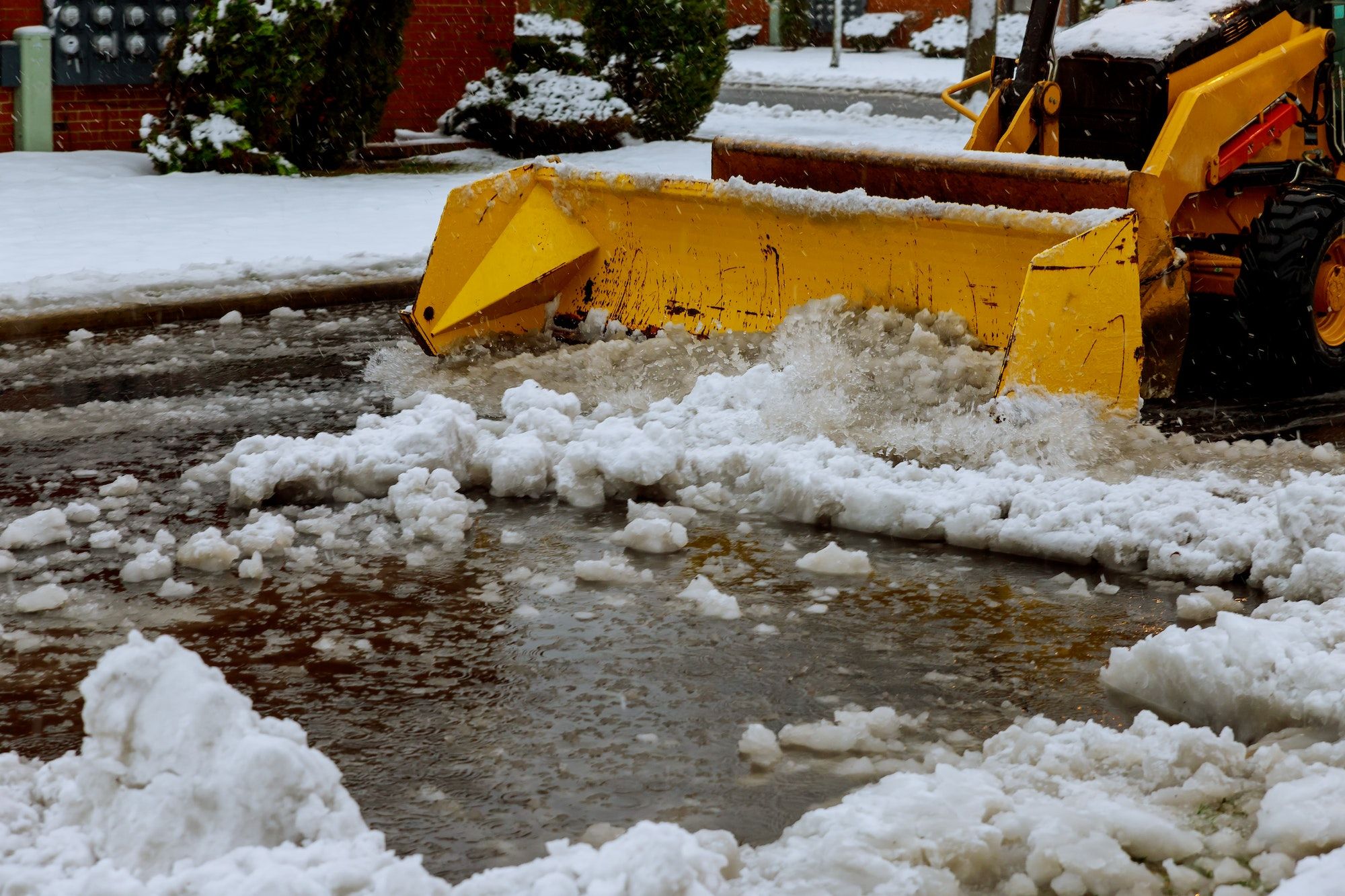 Snow plow truck clearing road after winter snowstorm blizzard for vehicle access